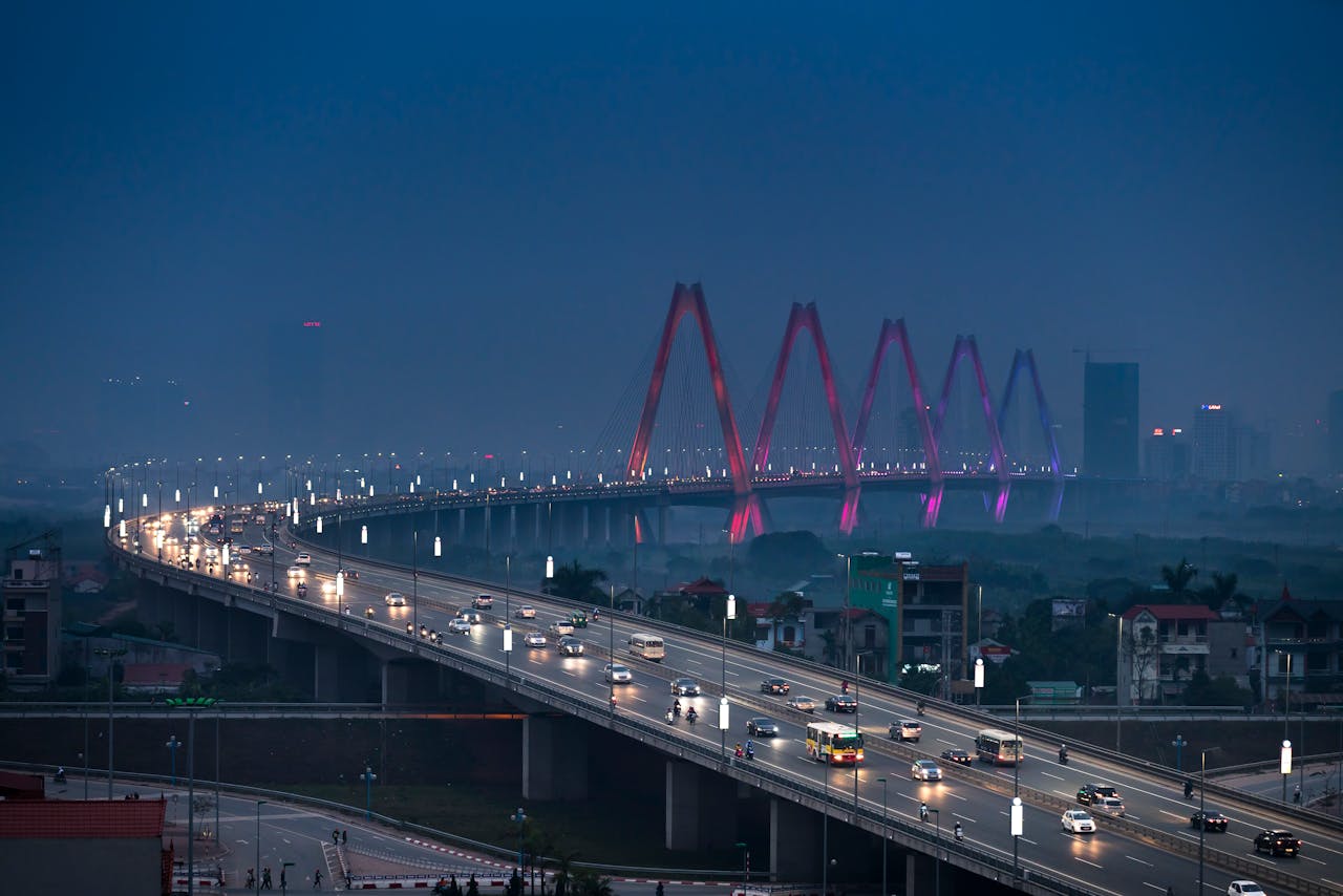 services-01 Scenic twilight view of an illuminated city bridge and road, capturing vibrant evening traffic.